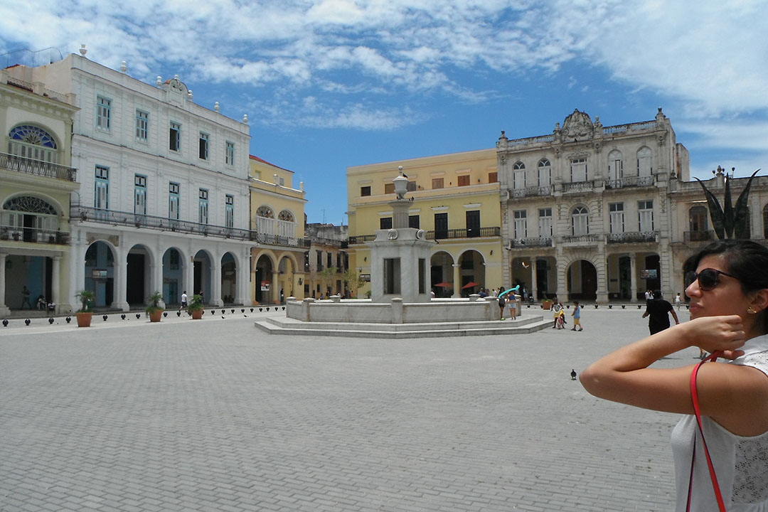 A student standing in a cobblestone plaza surrounded by historical buildings in Cuba